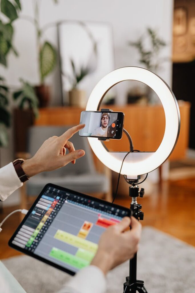 A content creator uses a smartphone and ring light setup for vlogging indoors.