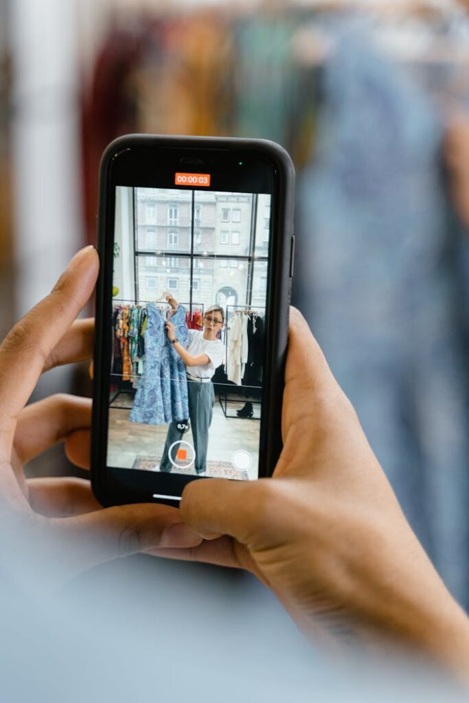 Woman recording video of a blue dress for online fashion business in airy studio.